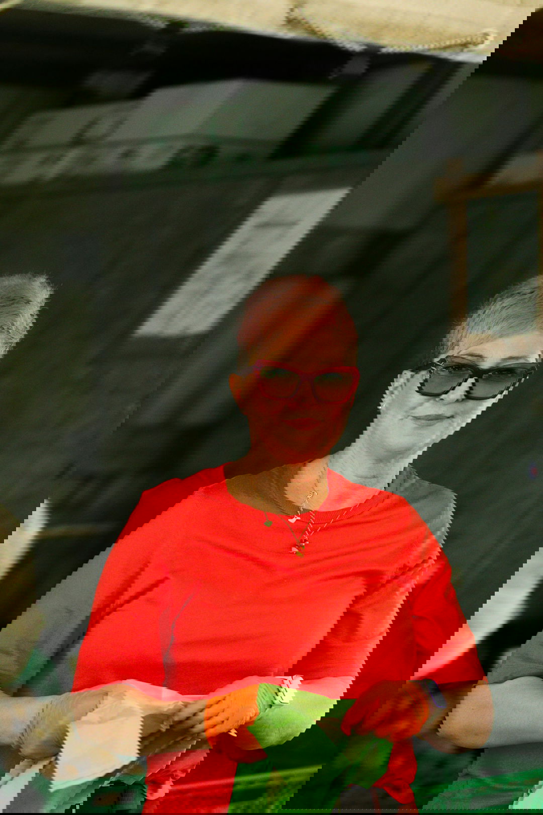 a woman in a red shirt is holding a green origami